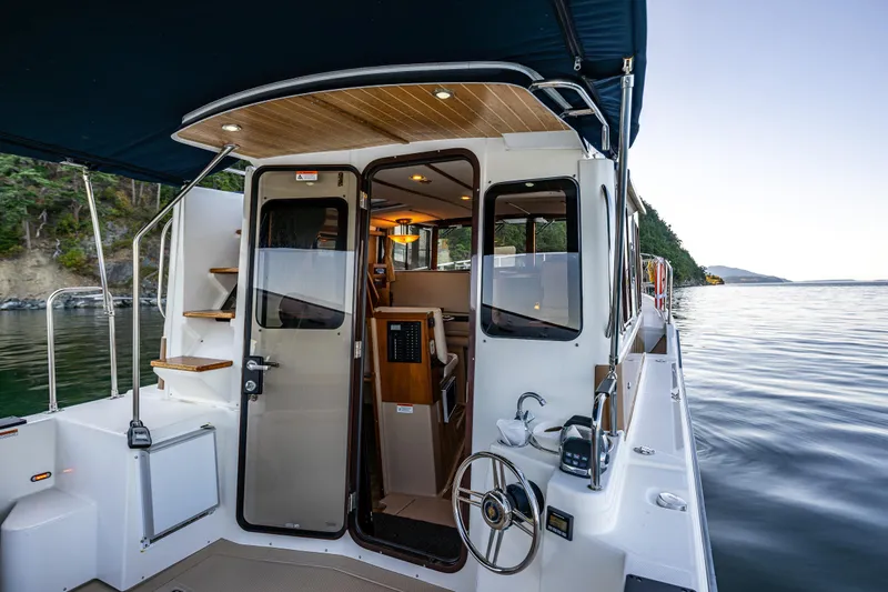 The Western Yacht Photos Pics 2014 Ranger Tugs R-31CB boat interior with open cabin door, docked by scenic shoreline.