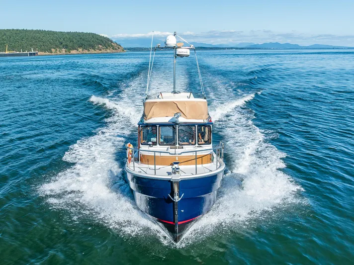 The Western Yacht Photos Pics 2014 Ranger Tugs R-31CB cruising on open water, scenic coastal background.