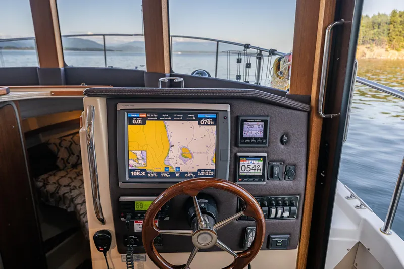 The Western Yacht Photos Pics 2014 Ranger Tugs R-31CB helm with navigation display and steering wheel on calm water.