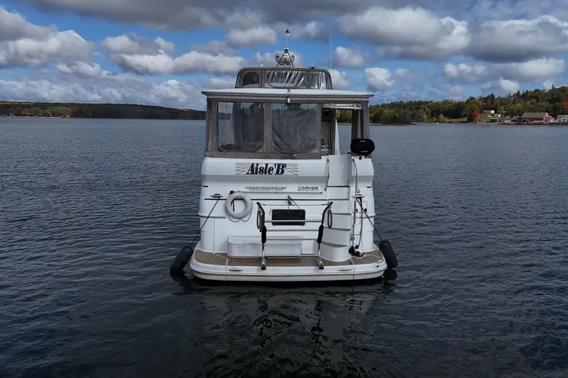  Yacht Photos Pics 2002 Carver 466 Motor Yacht on a serene lake under a cloudy sky.