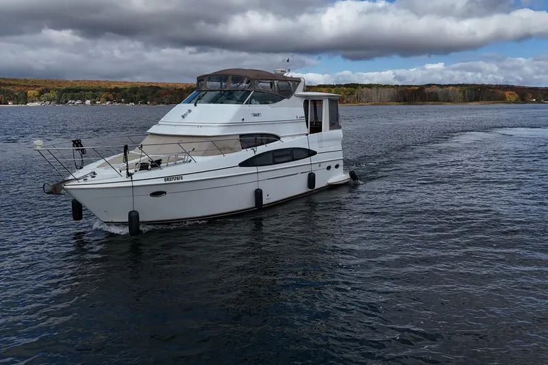  Yacht Photos Pics 2002 Carver 466 Motor Yacht cruising on a scenic lake under cloudy skies.