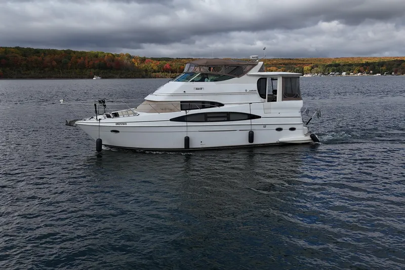  Yacht Photos Pics 2002 Carver 466 Motor Yacht cruising on a scenic lake under cloudy skies.