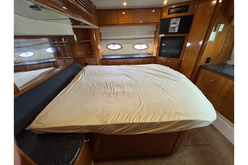  Yacht Photos Pics Interior of 2002 Carver 466 Motor Yacht bedroom with bed, wood cabinetry, and porthole windows.