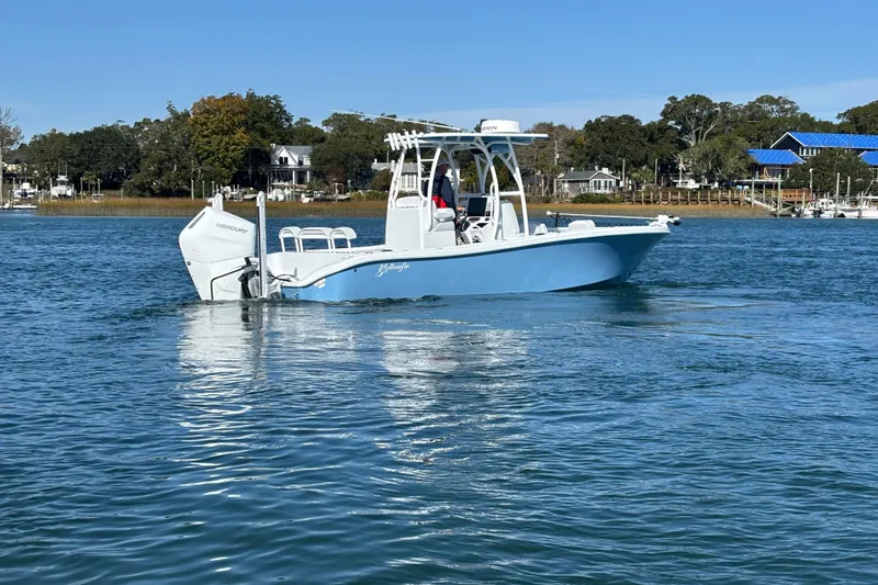  Yacht Photos Pics 2026 Yellowfin 26 Hybrid boat on calm water, with scenic shoreline background.