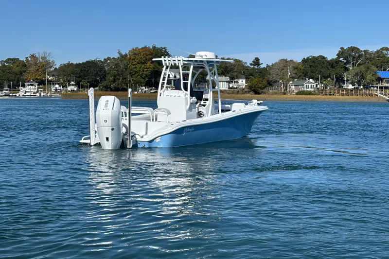  Yacht Photos Pics 2026 Yellowfin 26 Hybrid boat on calm water, surrounded by scenic shoreline.