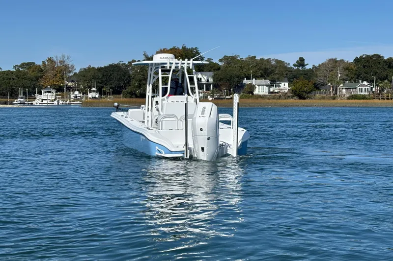  Yacht Photos Pics 2026 Yellowfin 26 Hybrid boat on calm water, surrounded by scenic shoreline.