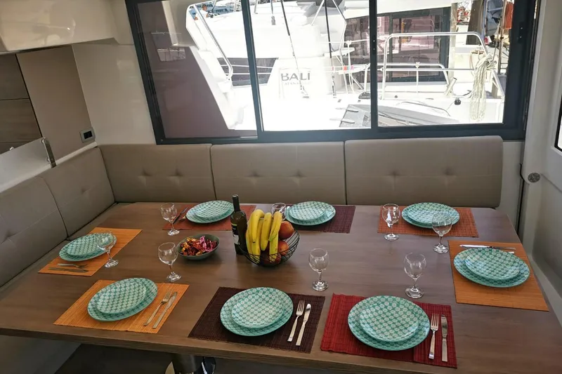 Eagle Yacht Photos Pics Dining area on 2022 Bali 4.8 yacht, set with plates, glasses, and fruit centerpiece.