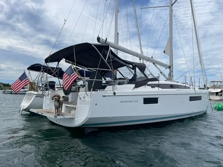 Shaz Yacht Photos Pics 2020 Jeanneau Sun Odyssey 410 sailboat with dog on deck, docked with American flags.