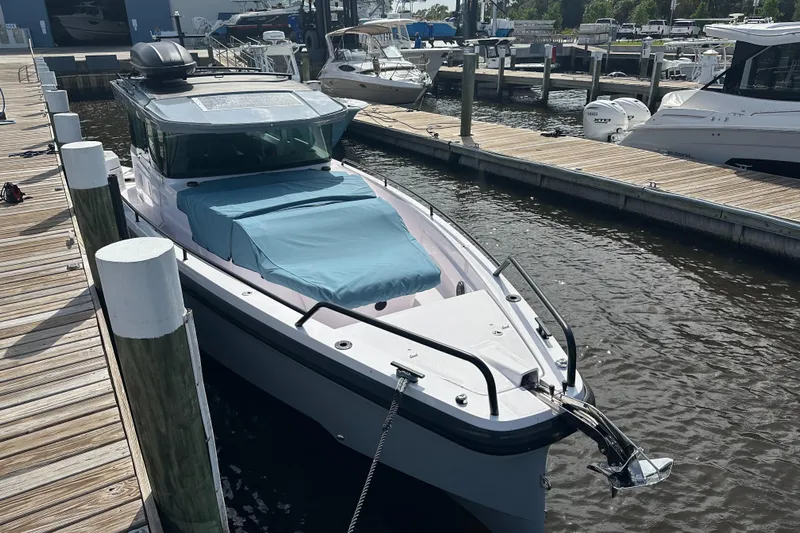  Yacht Photos Pics 2024 Axopar 37XC boat docked at marina, covered bow, sunny day.