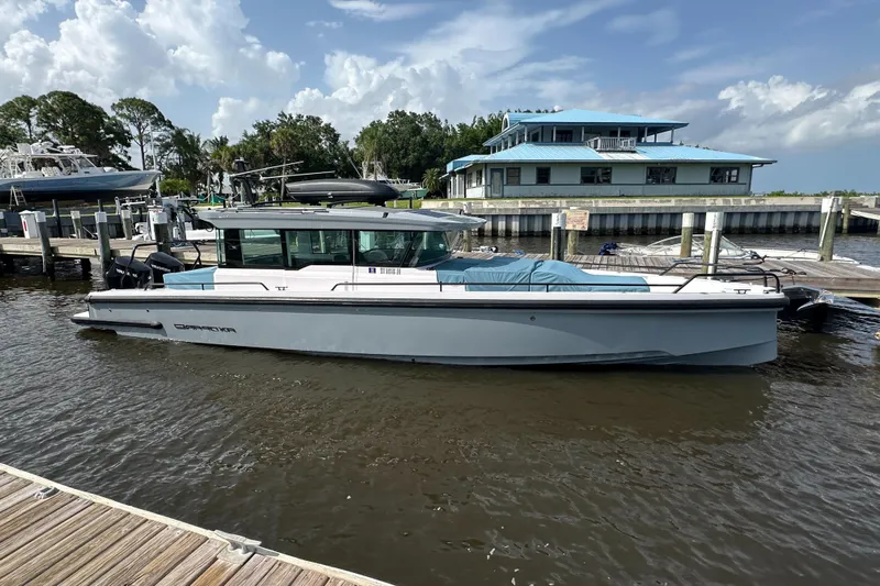  Yacht Photos Pics 2024 Axopar 37XC boat docked at marina, clear sky, waterfront building in background.