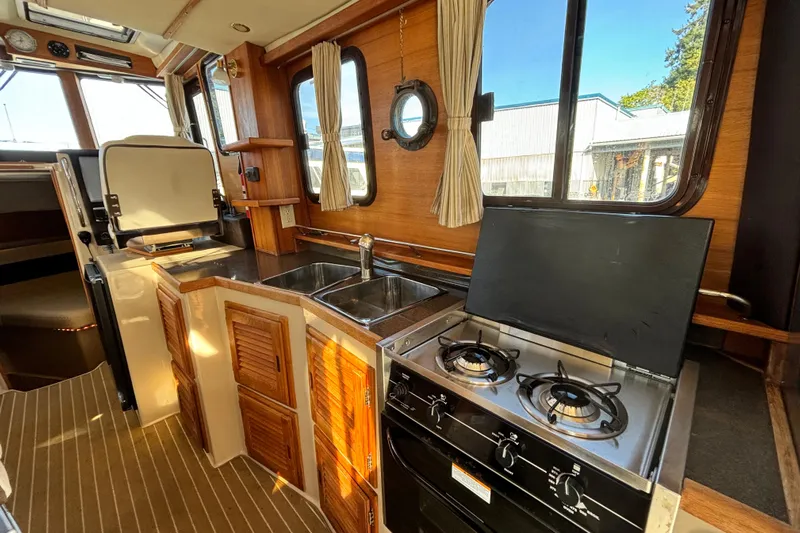  Yacht Photos Pics 2015 Ranger Tugs R-31 CB interior kitchen with stove, sink, and wooden cabinetry.