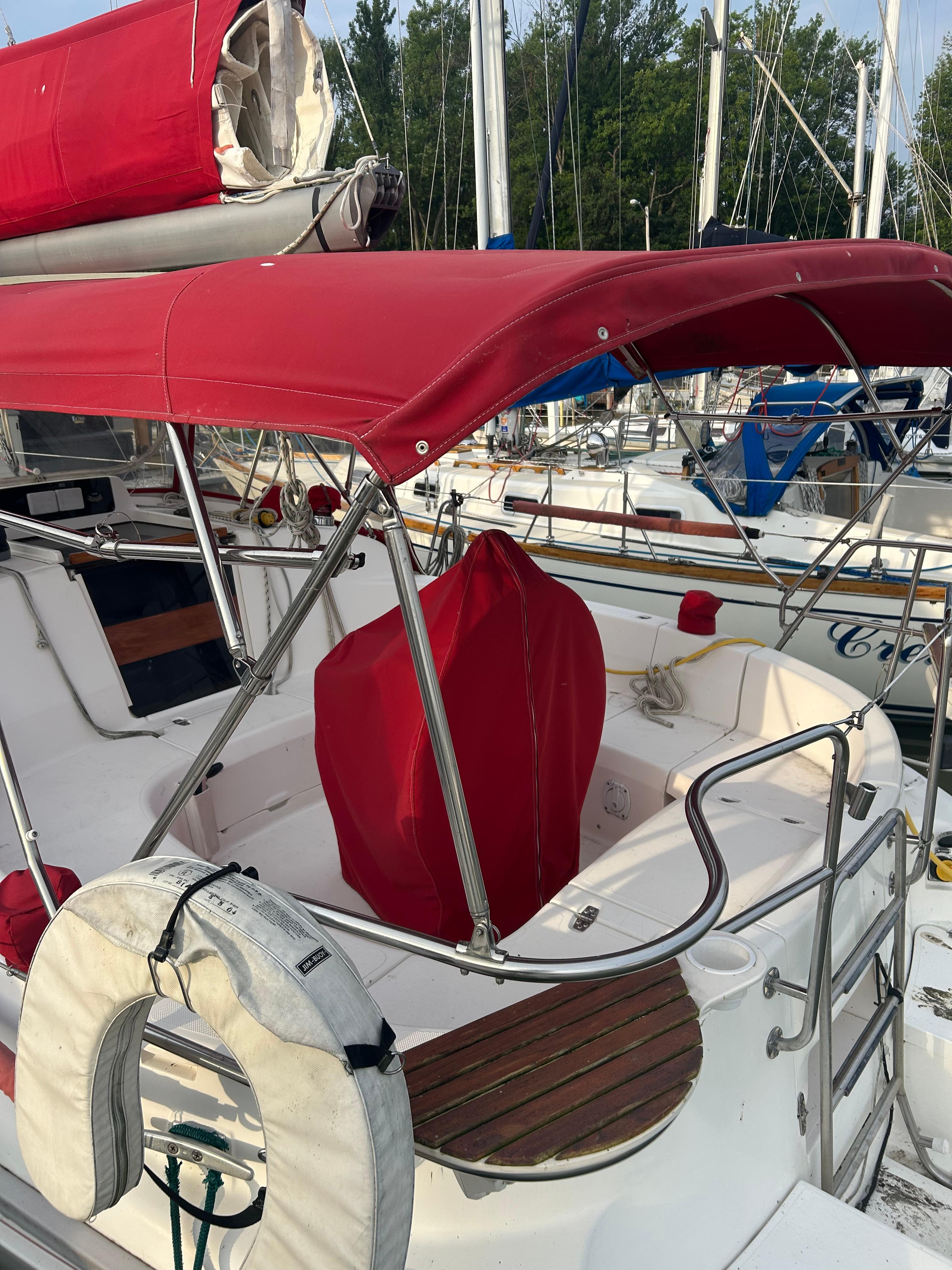 Sailboat cockpit with red canopy, Hunter 336, 1996 model, docked at marina.