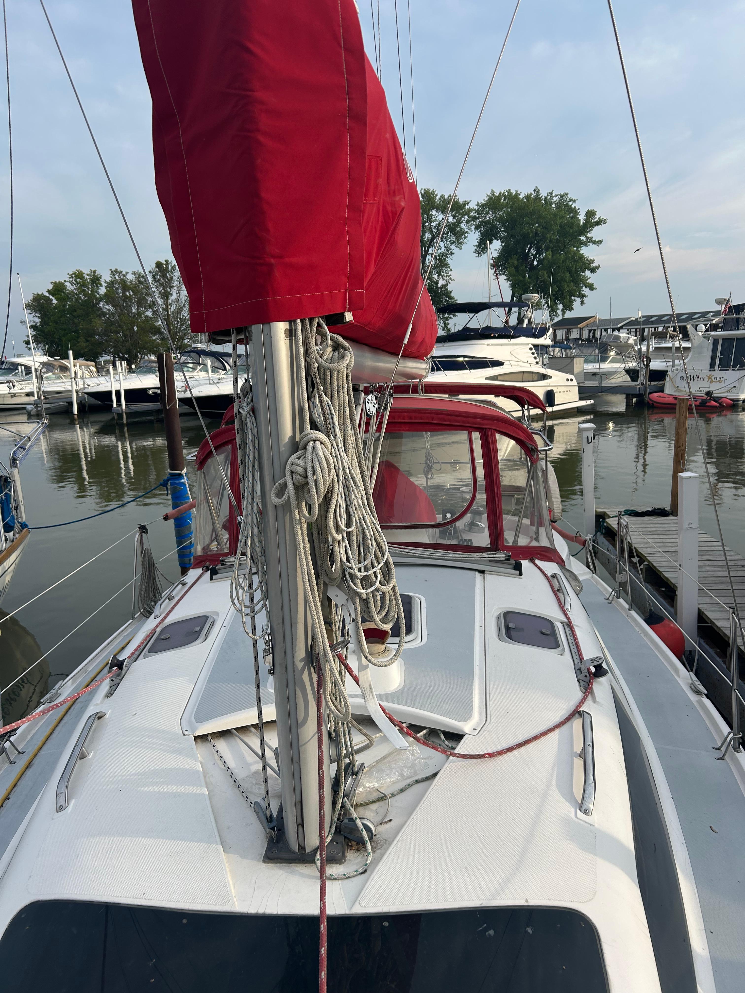 Sailboat Hunter 336, 1996 model, docked with red sail cover, marina background.