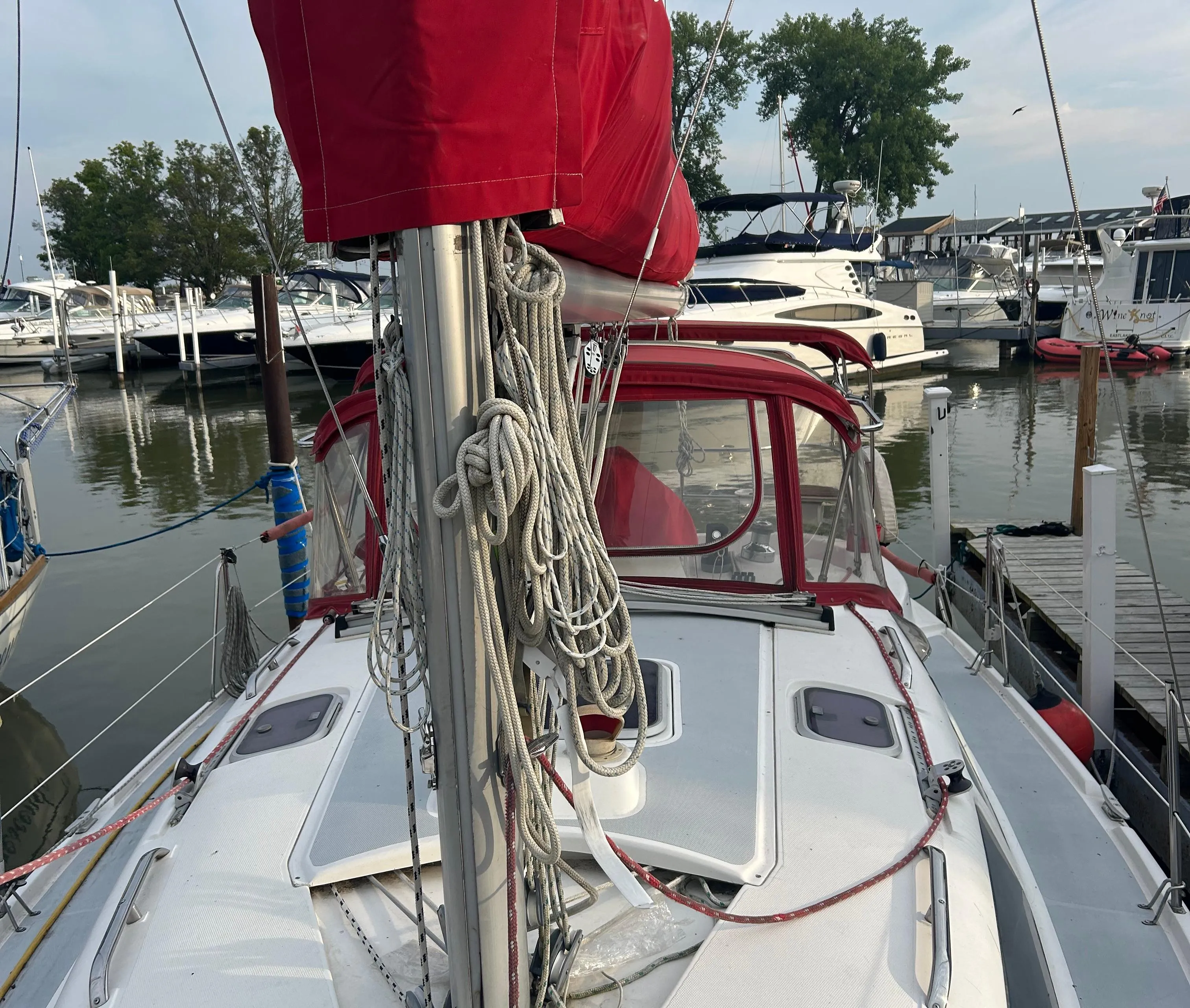 Sailboat Hunter 336, 1996 model, docked with red sail cover, marina background.