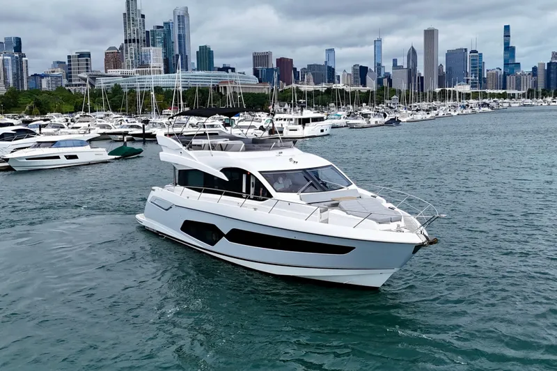  Yacht Photos Pics 2019 Sunseeker Manhattan 66 yacht cruising near city skyline and marina.