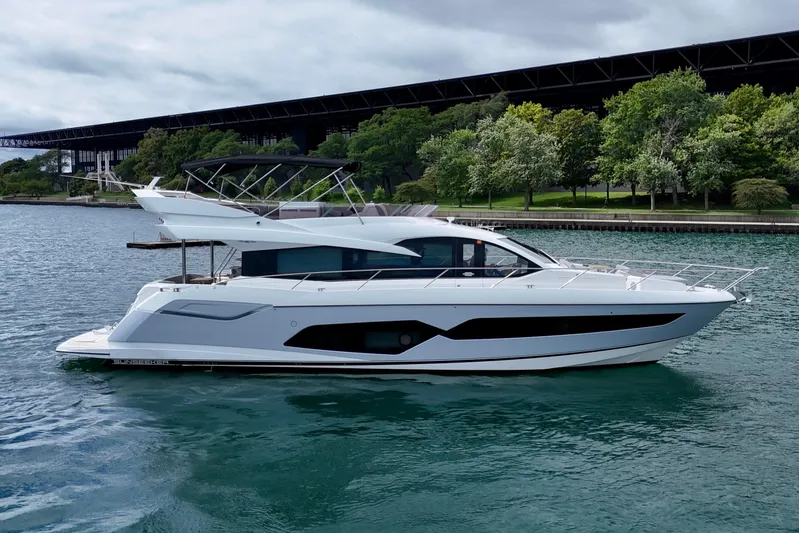  Yacht Photos Pics 2019 Sunseeker Manhattan 66 yacht on water, with trees and bridge in background.