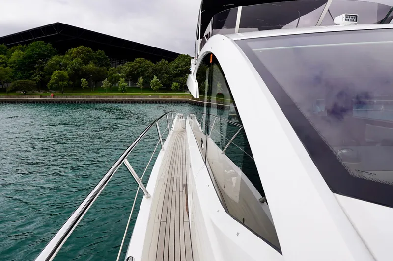  Yacht Photos Pics 2019 Sunseeker Manhattan 66 yacht on water, near lush green shoreline.