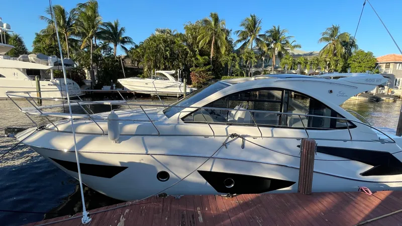  Yacht Photos Pics 2022 Evolve 400HT yacht docked by palm trees and waterfront homes.