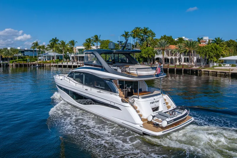 Her Way Yacht Photos Pics Luxurious 2023 Princess Y72 yacht cruising near waterfront homes under a clear blue sky.
