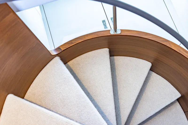 Her Way Yacht Photos Pics Curved wooden staircase with carpeted steps on a 2023 Princess Y72 yacht.