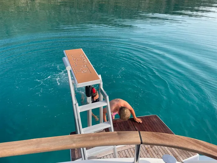 Kishta Yacht Photos Pics Person climbing ladder onto Fountaine Pajot Cumberland 46 yacht, 2009, in clear blue water.