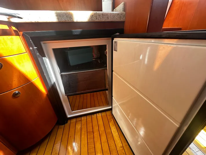  Yacht Photos Pics 2006 Chris-Craft 43 Roamer yacht interior with open mini fridge and wooden flooring.