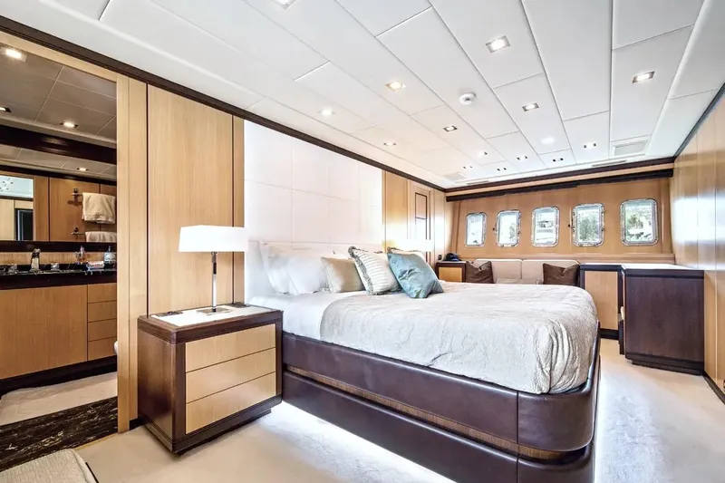 Daya Yacht Photos Pics Luxurious bedroom interior of 2007 Mangusta 105 yacht, featuring elegant wood paneling and modern lighting.