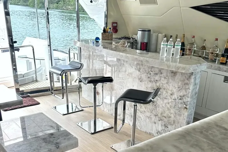 Daya Yacht Photos Pics Luxurious bar area on a 2007 Mangusta 105 yacht with marble countertops and modern stools.