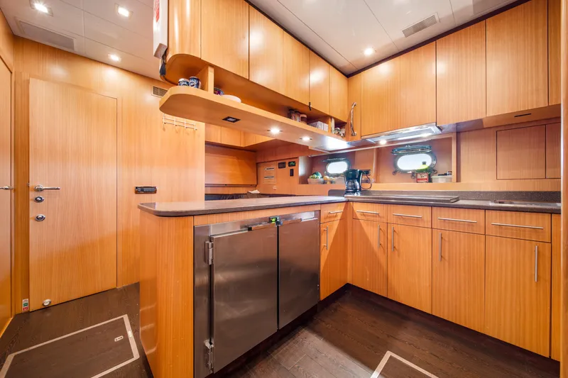 Daya Yacht Photos Pics Luxurious 2007 Mangusta 105 yacht kitchen with modern wood cabinetry and stainless steel appliances.