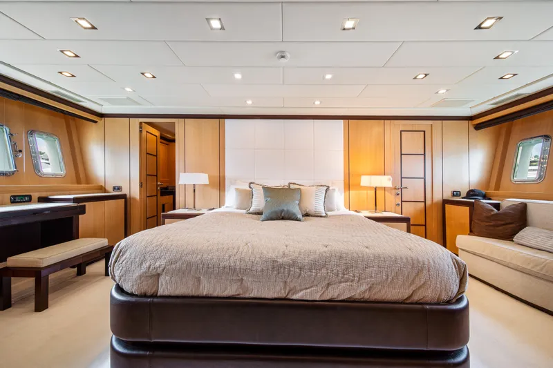 Daya Yacht Photos Pics Luxurious bedroom interior on 2007 Mangusta 105 yacht, featuring elegant wood paneling and modern lighting.