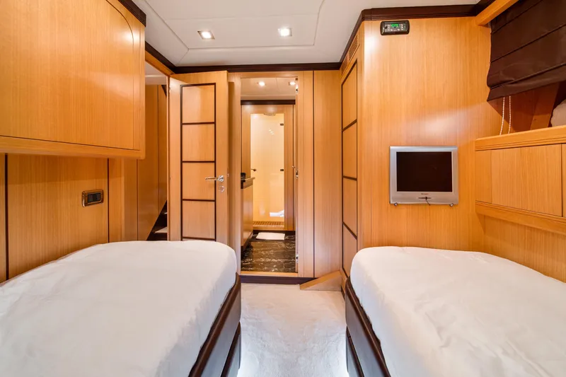 Daya Yacht Photos Pics Luxurious 2007 Mangusta 105 yacht cabin with twin beds and wooden interior.