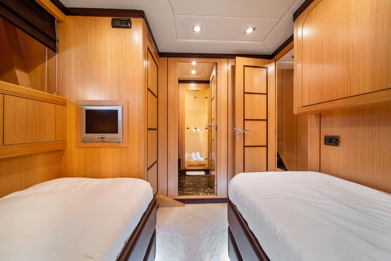 Daya Yacht Photos Pics Luxurious 2007 Mangusta 105 yacht cabin with twin beds and modern wood paneling.