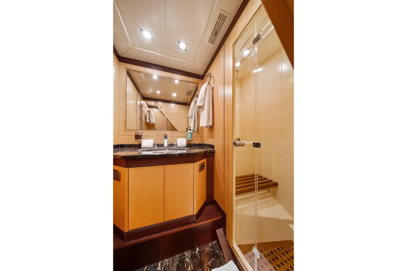 Daya Yacht Photos Pics Luxurious bathroom interior of 2007 Mangusta 105 yacht with wooden cabinetry and glass shower.