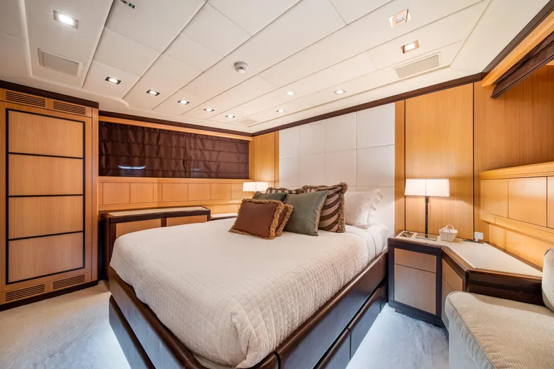 Daya Yacht Photos Pics Luxurious bedroom interior on 2007 Mangusta 105 yacht, featuring elegant wood paneling and ambient lighting.