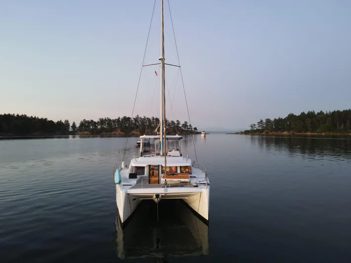 Neve Yacht Photos Pics 2022 Bali 4.6 catamaran on calm water, surrounded by trees and serene landscape.