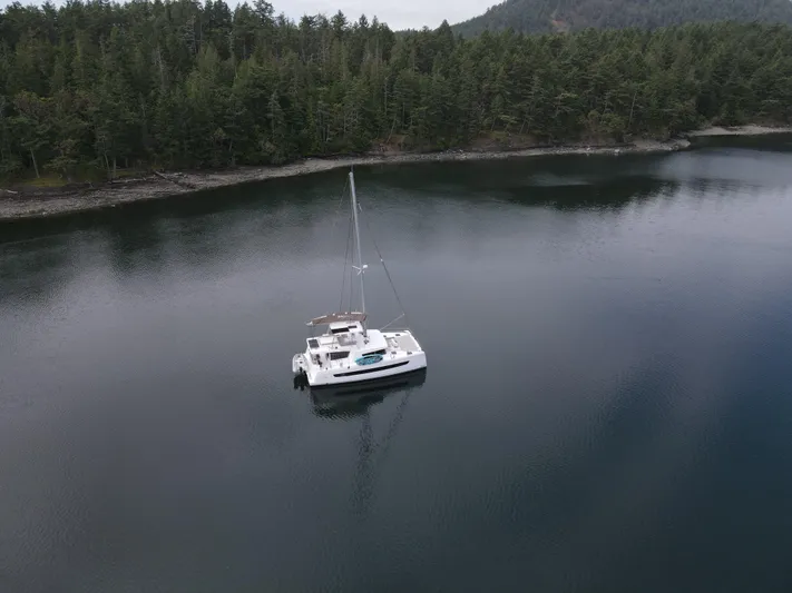 Neve Yacht Photos Pics Aerial view of 2022 Bali 4.6 catamaran anchored in serene forested bay.