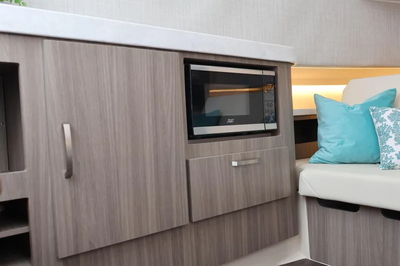  Yacht Photos Pics 2022 Regal 38 SAV interior with microwave, wood cabinetry, and decorative cushions.