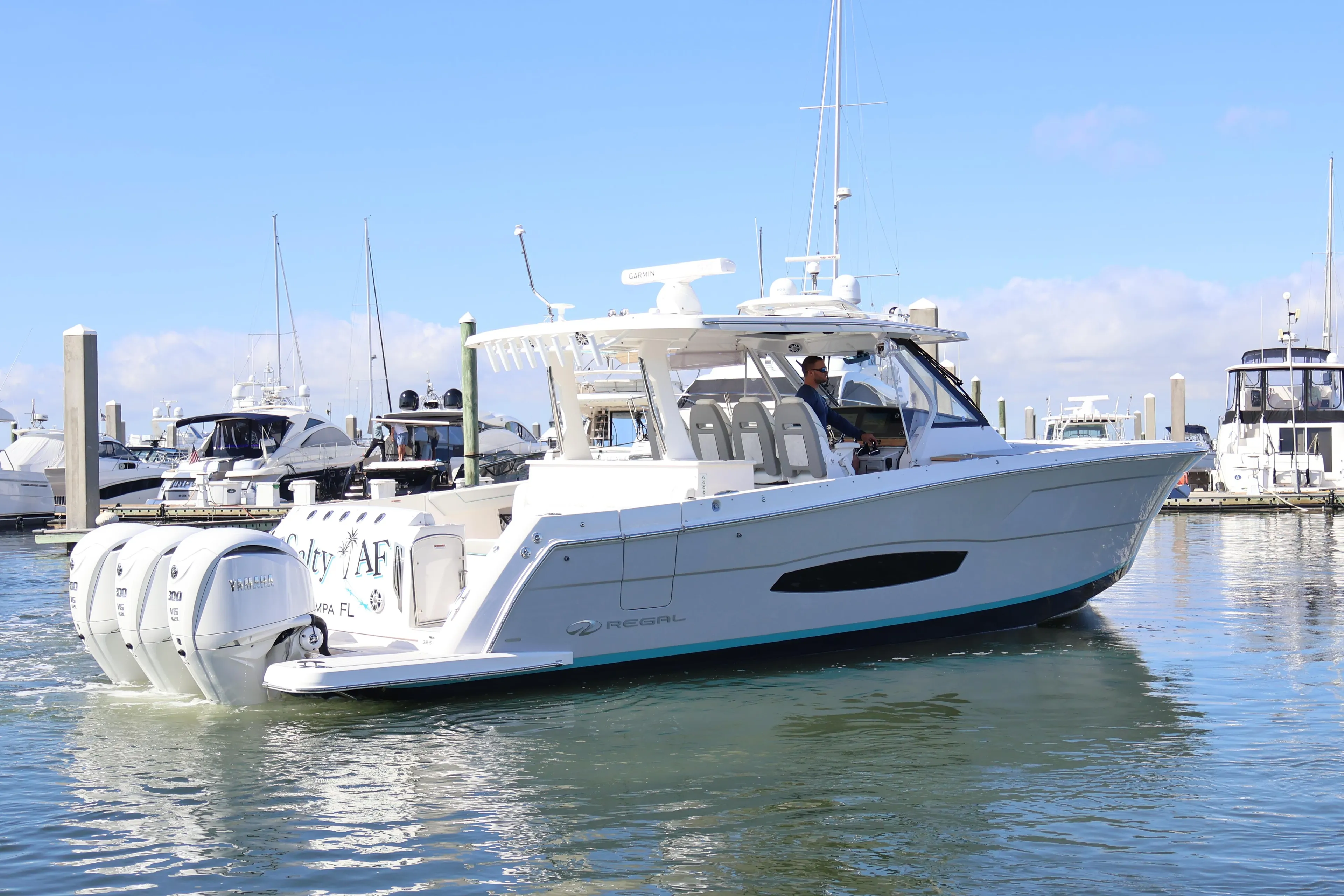 2022 Regal 38 SAV boat docked in marina with triple Yamaha outboard engines.