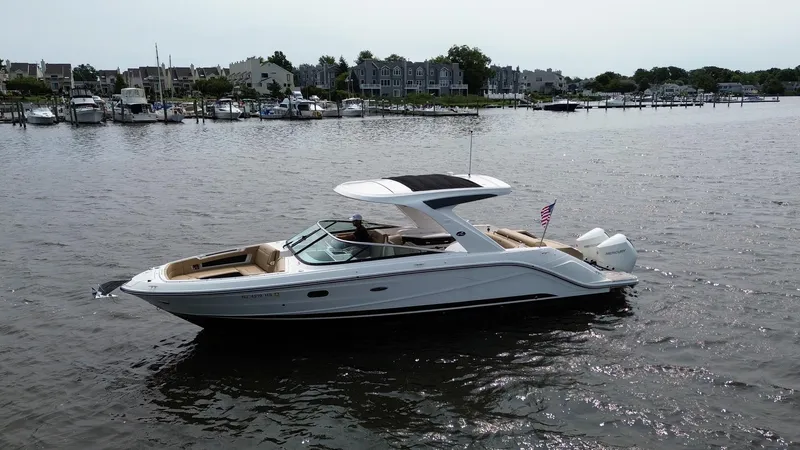  Yacht Photos Pics 2023 Sea Ray SLX 310 boat cruising on a calm river near a marina.