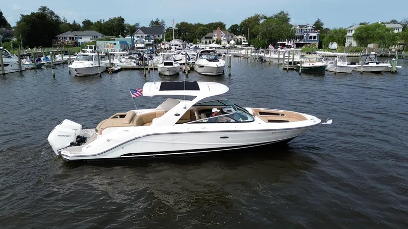  Yacht Photos Pics 2023 Sea Ray SLX 310 boat cruising in a marina with multiple docked boats.