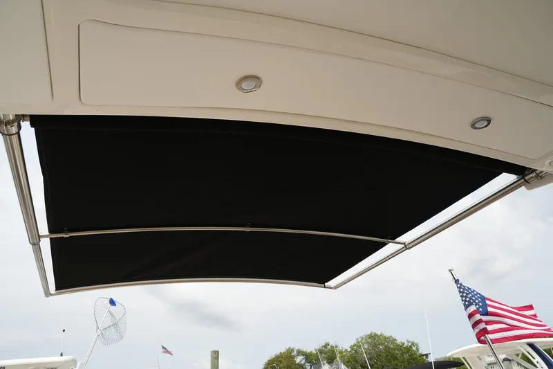  Yacht Photos Pics 2023 Sea Ray SLX 310 boat with extended black sunshade and American flag in background.