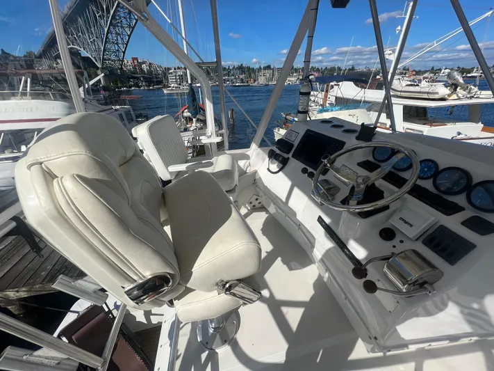 Uno Mas Yacht Photos Pics 2001 Luhrs 360 Convertible yacht helm with white seats and steering wheel, docked near a bridge.