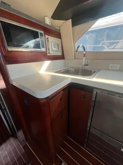 Uno Mas Yacht Photos Pics 2001 Luhrs 360 Convertible yacht kitchen with sink, microwave, and wooden cabinetry.