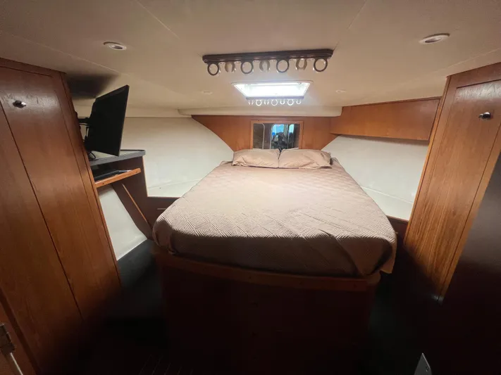 Uno Mas Yacht Photos Pics 2001 Luhrs 360 Convertible cabin interior with bed, wood paneling, and TV.