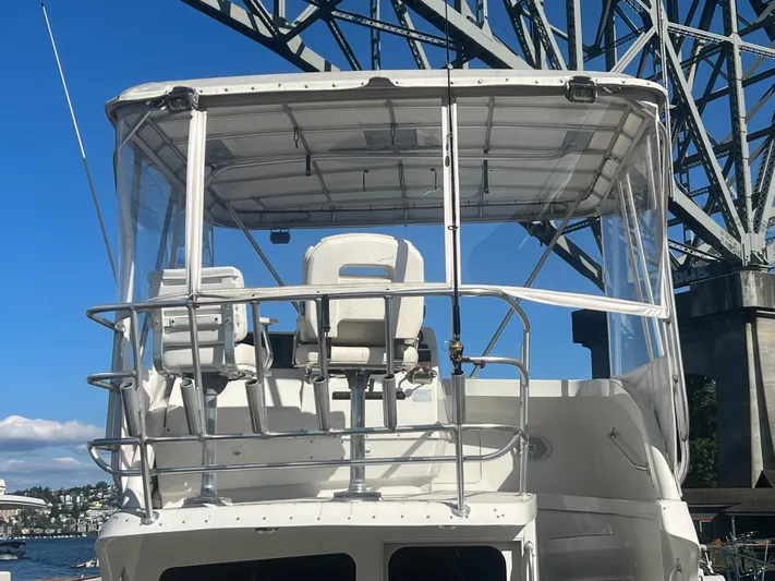 Uno Mas Yacht Photos Pics 2001 Luhrs 360 Convertible boat under a bridge, featuring a clear canopy and seating.
