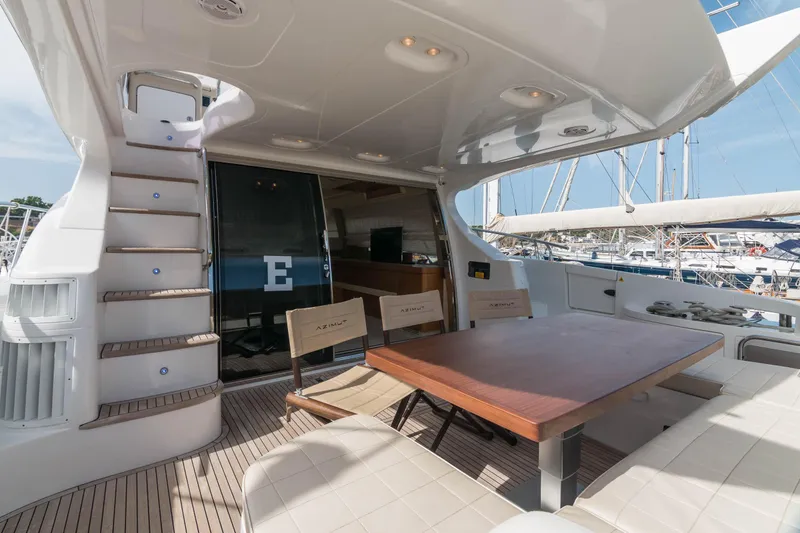 Elena Yacht Photos Pics 2013 Azimut 64 yacht deck with seating, table, and stairs, docked at marina.
