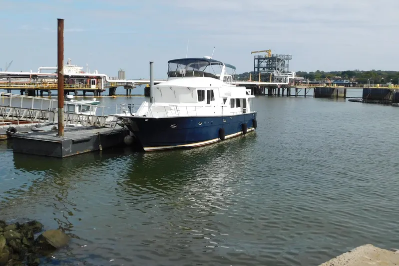Liquid Gold Yacht Photos Pics 2001 Jefferson Pilothouse 57 yacht docked at a marina with industrial background.