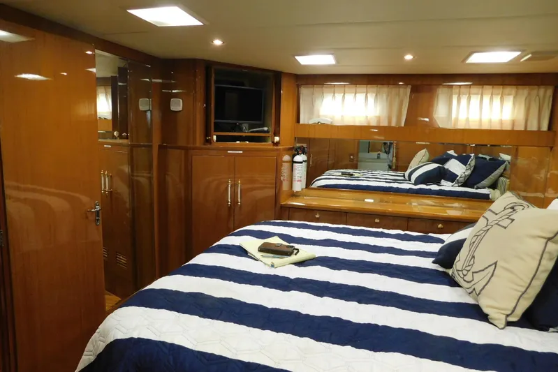 Liquid Gold Yacht Photos Pics Luxurious bedroom interior of 2001 Jefferson Pilothouse 57 yacht with striped bedding and wood finishes.