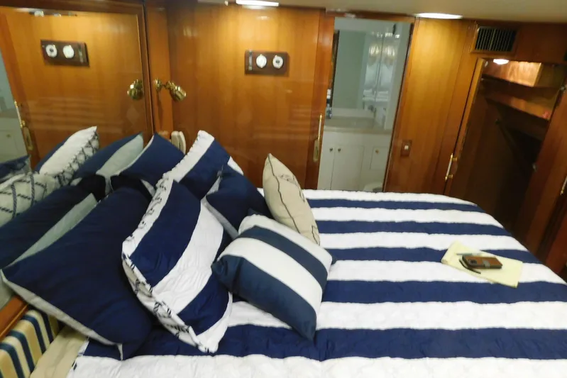 Liquid Gold Yacht Photos Pics Luxurious bedroom in 2001 Jefferson Pilothouse 57 yacht with striped bedding and wooden accents.