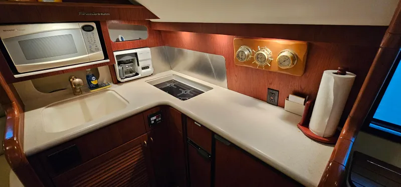Sunbeam Yacht Photos Pics 2002 Pursuit 3800 Express yacht kitchen with microwave, stove, and wooden cabinetry.